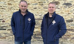 Deux hommes devant un mur de pierre