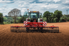 Un tracteur abec une houe attelée au travail dans un champ
