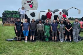 Des personnes devant une vache géante fabriquée avec des rounds