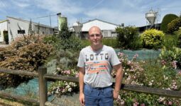 Un homme devant un jolie parterre de fleurs dans un élevage de porc
