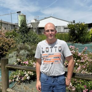 Un homme devant un jolie parterre de fleurs dans un élevage de porc