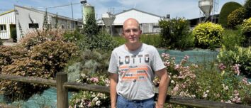 Un homme devant un jolie parterre de fleurs dans un élevage de porc