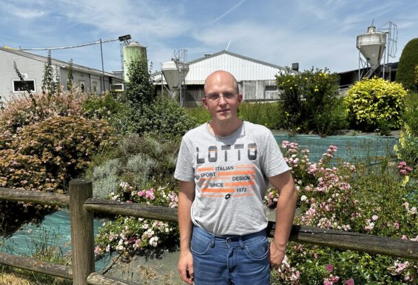 Un homme devant un jolie parterre de fleurs dans un élevage de porc