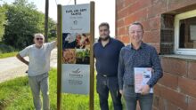 Trois hommes posent devant une pancarte