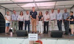 Un groupe de personnes sur une scène coupe un ruban d'inauguration
