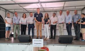 Un groupe de personnes sur une scène coupe un ruban d'inauguration