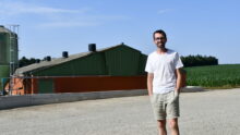 un homme devant un bâtiment d'élevage de porcs