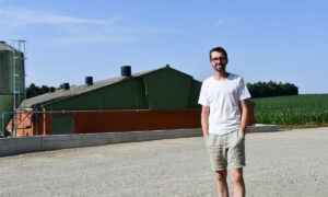un homme devant un bâtiment d'élevage de porcs