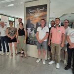 Des hommes et femmes devant une affiche