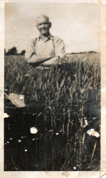 une photo ancienne avec un homme qui croise les bras au milieu des herbes hautes dans un champ