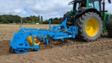 Un fissurateur attelé à un tracteur au travail dans un champ