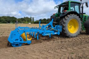 Un fissurateur attelé à un tracteur au travail dans un champ