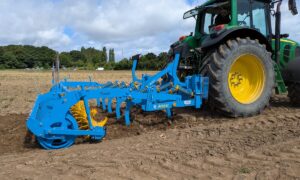 Un fissurateur attelé à un tracteur au travail dans un champ