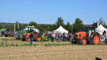 Des personnes qui regardent de démonstrations de travail au champ avec des tracteurs
