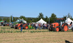 Des personnes qui regardent de démonstrations de travail au champ avec des tracteurs