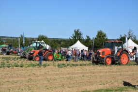 Des personnes qui regardent de démonstrations de travail au champ avec des tracteurs