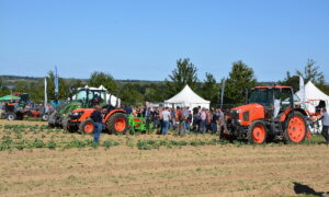 Des personnes qui regardent de démonstrations de travail au champ avec des tracteurs