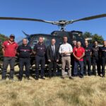 Des personnes devant un hélicoptère dans un champ