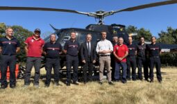 Des personnes devant un hélicoptère dans un champ