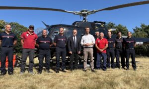 Des personnes devant un hélicoptère dans un champ