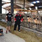 Deux hommes devant des cornadis avec des robots dans le fond