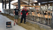 Deux hommes devant des cornadis avec des robots dans le fond