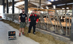 Deux hommes devant des cornadis avec des robots dans le fond