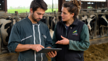 Un agriculteur avec une tablette dans les main et une conseillère dans une stabulation