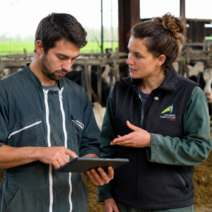 Un agriculteur avec une tablette dans les main et une conseillère dans une stabulation