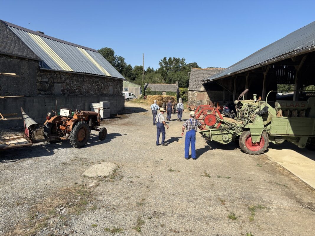 Une cour de ferme avec des personnes et du matériel agricole