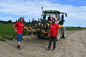 Deux producteurs de légumes debout devant un tracteur dans un champ de production