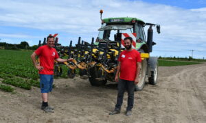 Deux producteurs de légumes debout devant un tracteur dans un champ de production