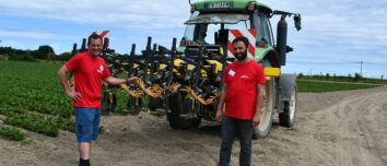 Deux producteurs de légumes debout devant un tracteur dans un champ de production