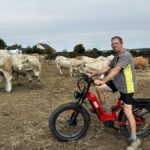 Un éleveur à vélo au milieu de ses vaches