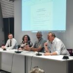 Une femme et trois hommes à une tribune
