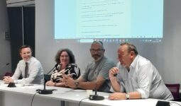 Une femme et trois hommes à une tribune
