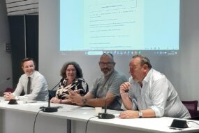 Une femme et trois hommes à une tribune