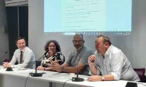 Une femme et trois hommes à une tribune