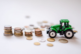 Un tracteur miniature avec des piles de pièces de monnaie