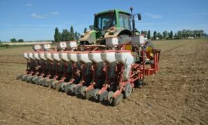 Un tracteur avec un semoir attelé au travail dans un champ
