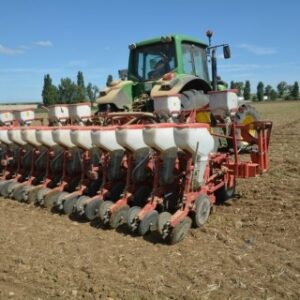 Un tracteur avec un semoir attelé au travail dans un champ