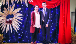 Un couple prend la pose devant un fond de tissus colorés