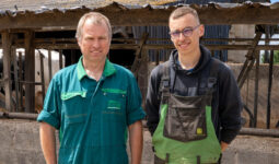Deux hommes posent devant un ratelier dans une ferme