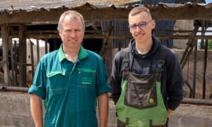 Deux hommes posent devant un ratelier dans une ferme
