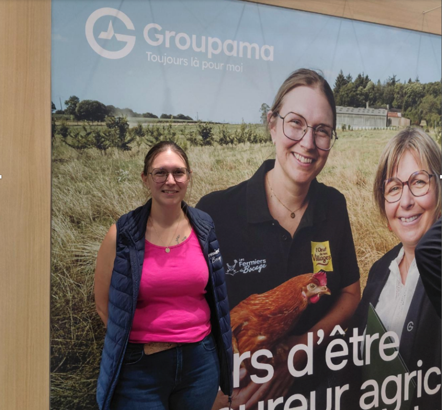 Une femme pose devant une affiche où elle figure