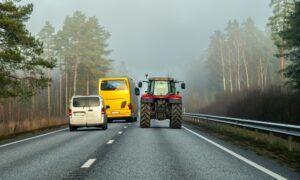 Un bus et un van en train de doubler un tracteur sur une route à 2 voies