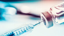 Gros plan sur une seringue qui prélève du liquide dans un flacon de vaccin