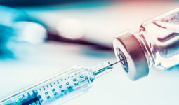 Gros plan sur une seringue qui prélève du liquide dans un flacon de vaccin