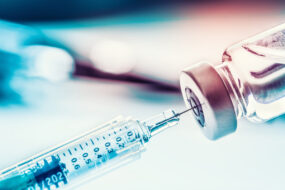 Gros plan sur une seringue qui prélève du liquide dans un flacon de vaccin