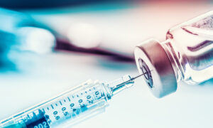 Gros plan sur une seringue qui prélève du liquide dans un flacon de vaccin